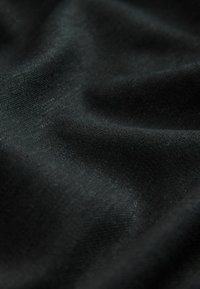 Zwarte stof met een gladde, licht glanzende textuur, met een fijne structuur en subtiele glans. Het materiaal lijkt zacht en valt gemakkelijk.