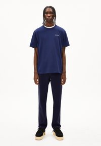 Navyblauwe katoenen T-shirt met een ronde hals, korte mouwen en een subtiel logo. Gecombineerd met donkerblauwe broek en zwarte platform schoenen.