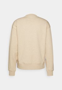 Sudadera beige con cuello redondo, mangas largas y puños de canalé. Tejido texturizado con un acabado suave. Diseño simple y minimalista.