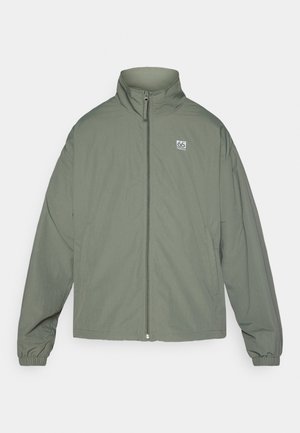 Olivgrüne Jacke mit hohem Kragen, Frontreißverschluss und elastischen Bündchen. Verfügt über ein kleines Logo auf der linken Brust und einen lockeren, lässigen Schnitt.
