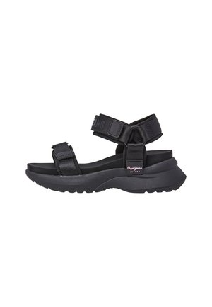 Sort sandal med justerbare stofstropper. Tykk sål med tekstureret overflade. Markant branding på stropper og sidesål. Moderne design.