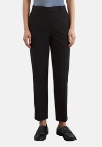 Zwarte op maat gemaakte broek met een recht model, textuurstof, zijzakken en een soepele tailleband, aangevuld met zwarte instappers.