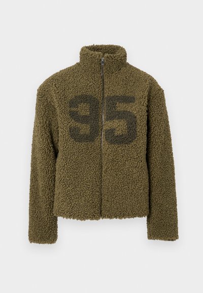 Giacca in pile verde oliva con collo alto, chiusura zip e design cropped. Presenta un grande "95" nero stampato sulla parte anteriore.