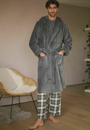 Grau strukturierter Bademantel mit Kapuze und Bindegürtel, mit zwei vorderen Taschen; getragen über karierten Schlafanzughosen in Grün und Weiß.