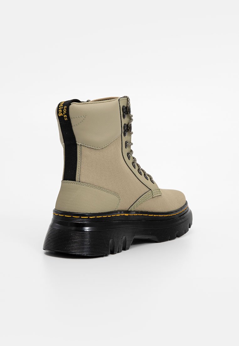 Bottines beiges avec un dessus en tissu texturé, semelle en caoutchouc noir et bout rond. Présente des lacets noirs et des accents de coutures jaunes.