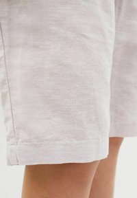Lätta linshorts med en slät struktur, med raka fållar och en subtil ljusrosa färg. Avslutade med enkla sömnadsdetaljer.