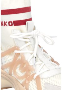 Bijele tenisice s mrežastim gornjim dijelom, ružičastim gumenim detaljima i bijelim vezicama. Imaju crveno prugasti čarapa s logotipom iznad gležnja. Teksturirana potplat.