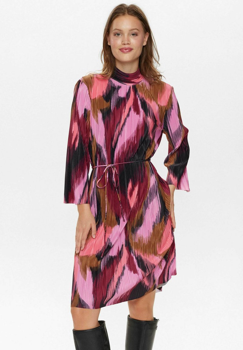Mehrfarbiges Faltenkleid mit hohem Kragen, langen Ärmeln und verstellbarem Bund. Die Muster enthalten rosa, schwarz und braune Farbtöne.