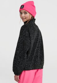 Musthave mustra tekstuurne must fleece'ist pullover kõrge kaelusega. Sobitub erksate roosa kudumismütsiga, millel on väike must logo kapp.