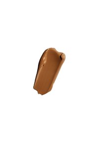 Échantillon de maquillage marron, texture crémeuse, application lisse, avec un bord supérieur arrondi et une forme irrégulière. Présenté sur un fond blanc.
