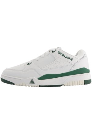 Zapatilla blanca con acentos verdes. Parte superior de cuero suave con detalles perforados. Punta redonda, cierre con cordones y suela de goma texturizada.