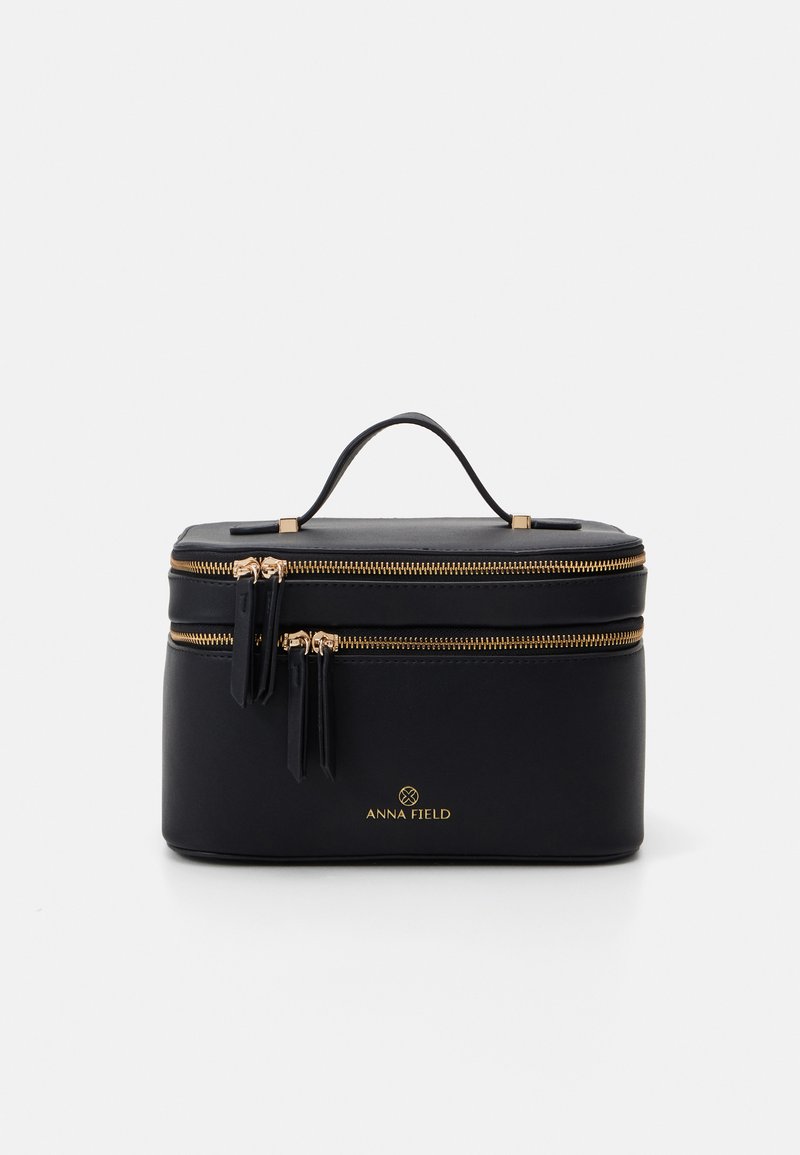 Bolso de cosméticos negro con doble cierre dorado, asa en la parte superior, superficie texturizada y logo dorado en el frente.
