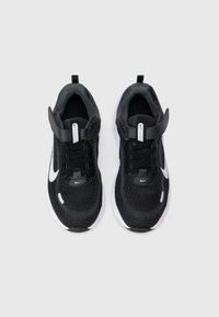 Czarne buty sportowe z teksturowaną cholewką z dzianiny, białym logo Nike Swoosh, wiązanym zapięciem i wyściełanym kołnierzem. Lekkie, z kontrastującą białą podeszwą.