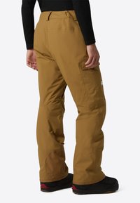 Brune vandtætte skibukser med en afslappet pasform, der har cargolommer, forstærket kant og logodetalje på siden.