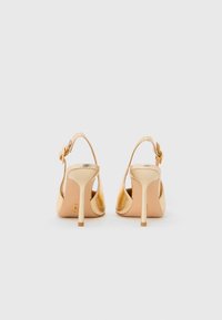 Chaussures à talons hauts en métal doré avec un dos ouvert et une bride de cheville, présentant un design épuré et une finition brillante.