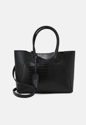 Sac à main en cuir noir à texture crocodile, doubles poignées, une bandoulière amovible et une étiquette d'identification suspendue sur fond blanc.