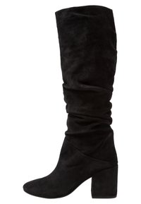 Svarta knähöga stövlar i mocka med en slapp skaft och klack, visade i sidoprofil på en vit bakgrund.