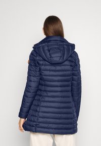 Merellinen vuorattu takki hupulla, joka sisältää tikatun muotoilun, pitkät hihat ja tiukan siluetin. Mukana teksturoitu kangas ja kestävä varustus.