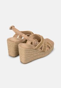 Sandales compensées beiges avec plateforme en jute tressé, brides croisées et bride de cheville réglable. Texture douce avec un design à bout carré.
