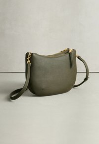 Olivgrüne Leder-Umhängetasche mit abgerundeter Form, strukturierter Oberfläche, Reißverschlüssen in Goldoptik und abnehmbarem Riemen.