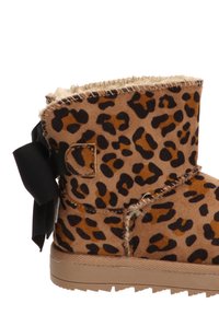 Botín de tobillo de estampado de leopardo hecho de ante, con un estilo de lazo negro, bordes cosidos y suela de goma color beige.