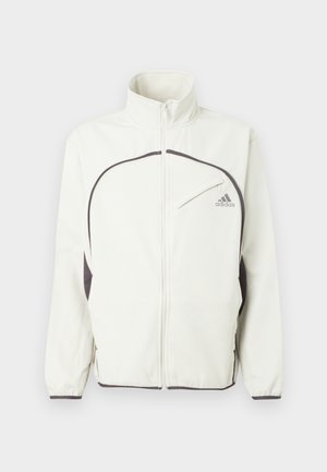 Λευκή ζακέτα με φερμουάρ και μαύρες λεπτομέρειες, με ψηλό γιακά, ελαστικούς καρπούς και λογότυπο σε γκρι στο αριστερό στήθος. Υφή υφάσματος.