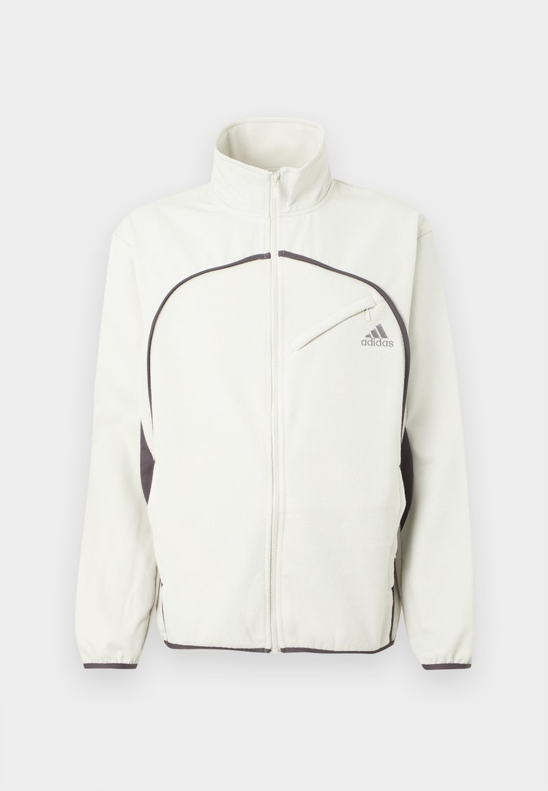 Witte ritsjack met zwarte accenten, voorzien van een staande kraag, elastische manchetten en een logo op de linkerkant van de borst in het grijs. Textuur van de stof.