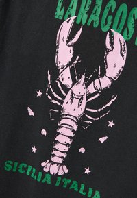 Czarna bawełniana koszulka z różowym nadrukiem homara i zielonym napisem "LACOSTE" oraz "SICILIA ITALIA", z małymi detalami muszelek i gwiazdek.