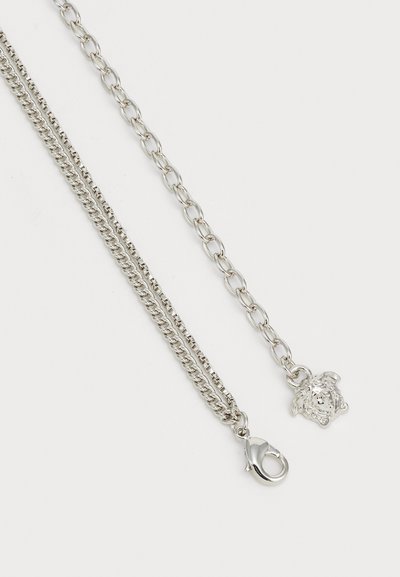 Colar de corrente prateada com dois estilos de design: uma corrente torcida em espiral e uma corrente de elos lisos, apresentando um fecho decorativo em forma de cabeça de leão.