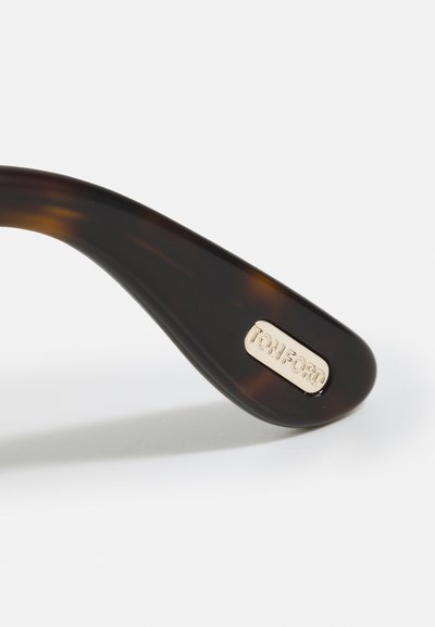 Brațul ochelarilor de soare din scoică are o finisare netedă și dispune de o placă logo „TOM FORD” cu ton auriu integrată. Design curbat și elegant.
