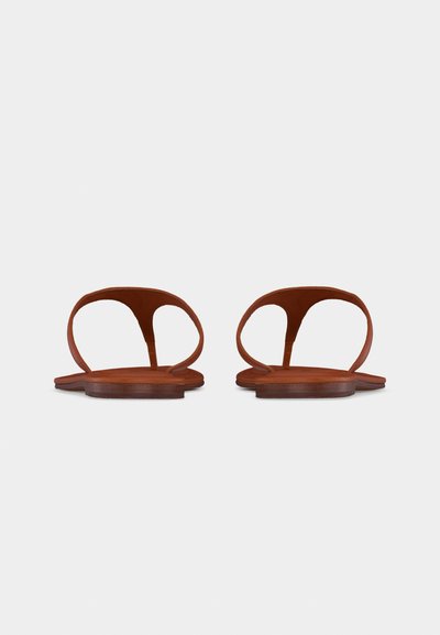 Ζευγάρι καφέ επίπεδων σανδαλιών με στρογγυλεμένες ανοιχτές φτέρνες και λεπτά λουριά, απεικονισμένο από μπροστά σε απλό λευκό φόντο.