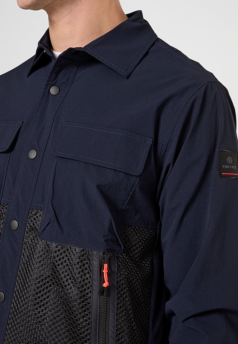 Marinejacke mit einem Netzunterteil, zwei Brusttaschen und orangefarbenem Reißverschluss-Zug, aus leichtem Stoff mit einem strukturierten Kragen.