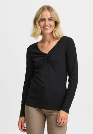 Top lungo nero a maniche lunghe con scollo a V e dettaglio arricciato al centro, realizzato in tessuto a costine con una silhouette aderente.