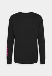 Svart långärmad t-shirt i bomull, med rundad halsringning och en rosa grafisk design på vänster ärm.