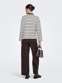 Chemise à manches longues rayée crème et marron, pantalon large marron foncé, et un petit sac à main texturé, vus de dos.