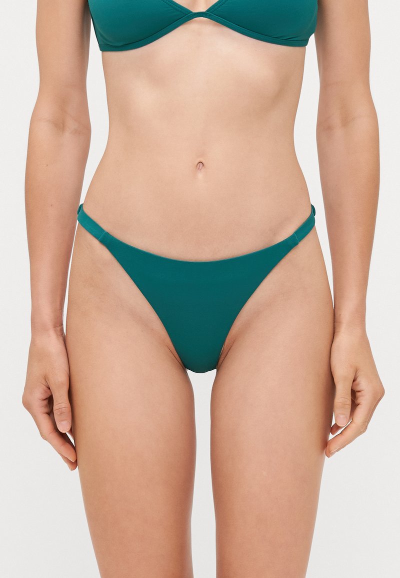 Teal bikini bottom made of smooth material, featuring slim side straps and a minimalistic design, offering a low-rise fit.