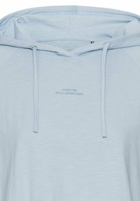 Lichtblauwe pullover hoodie van zacht materiaal met een trekkoord, voorzien van een tekstdetail aan de voorkant dat zegt "MADE FOR DAILY ADVENTURES."