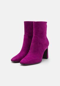 Fuchsialila mocka ankelskor med spetsig tå, hög blockklack och slät textur. Enkla sömmar och ingen synlig hårdvara eller dekorationer.