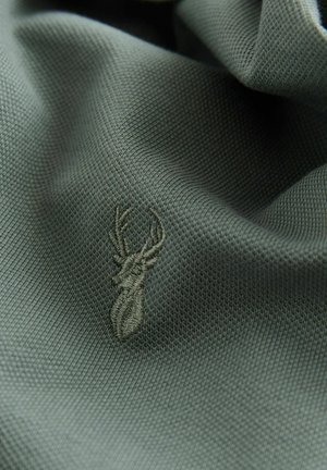 Dunkelgrüner Stoff mit strukturierter Webart, der ein gesticktes Hirschdesign in einem etwas helleren Grün zeigt.