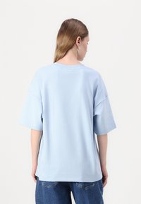 Light blue oversized t-shirt with short sleeves, crew neck, and a smooth cotton texture. It features a relaxed fit and clean hemline.