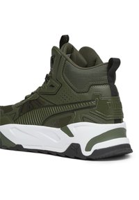 Hochformatige grüne Sneaker mit schwarzen Akzenten, dicker, weißer Sohle, Mesh-Gewebe und Zuglaschen an Ferse und Zunge.