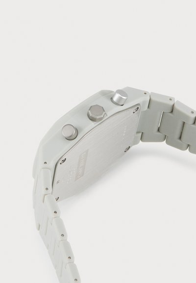 Light grey plastic watch with a stainless steel back, featuring two push buttons and a flexible link band. Notable hexagonal accent on the side.
