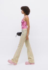 Rosa tank topp med fet skrift, lyseblå, utsvungne jeans og rosa klomper, sammen med en liten svart crossbody-veske.