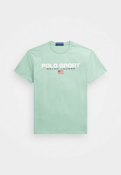 Hele rohelise puuvillase t-särgi esiküljel on valged ja mereväe sinised "POLO SPORT" ja "RALPH LAUREN" logod ning väike Ameerika lipu detail. Lühikesed varrukad.