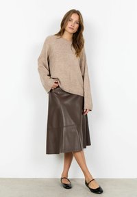 Ljust brunt oversized tröja med långa ärmar, parat med en mörkbrun imitationläder midi kjol med sömdetaljer, kompletterad med svarta ballerinas.
