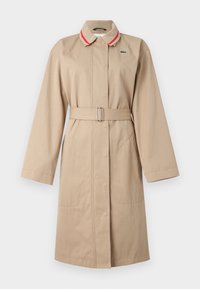 Trench coat beige con cintura in un tessuto leggero. Presenta un colletto con righe rosse e bianche, chiusura a bottoni e due tasche frontali.