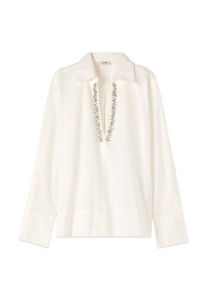 Blouse blanche à manches longues avec col et décolleté en V profond ornée de broderies florales argentées.