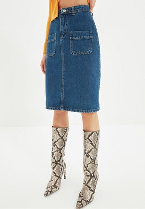 Mid-length blue denim skirt with front patch pockets, paired with knee-high snakeskin-patterned high-heeled boots.