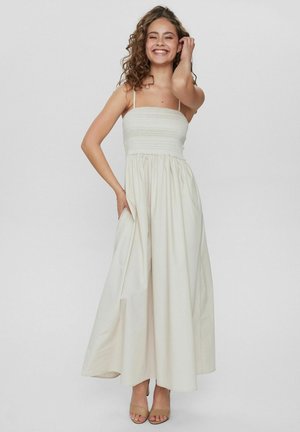 Hüftlanges, cremefarbenes Kleid mit gerafftem Oberteil, Spaghetti-Trägern und einem fließenden Rock. Verfügt über seitliche Taschen und einen leichten Stoff.