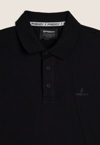 Polo negro hecho de algodón con un acabado texturizado, presenta un cuello, una tapeta de tres botones y un pequeño logo en el pecho.